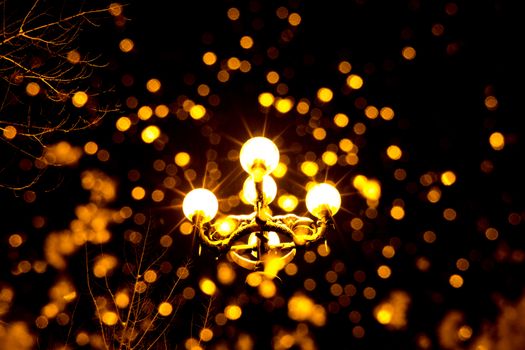 Antique yellow lantern at night with snow flakes falling down in the foreground.