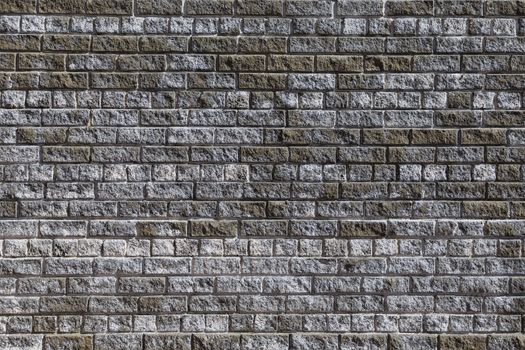 Brick wall made of grey and dirty white bricks. Full size front view.