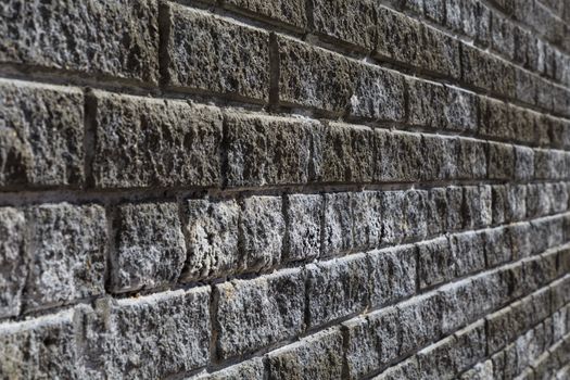 Front close-up view of a brick vintage wall at a 45 degree angle. Bricks are grey and white.