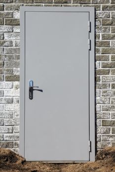 Grey steel entrance door built in a brick wall of a bunker