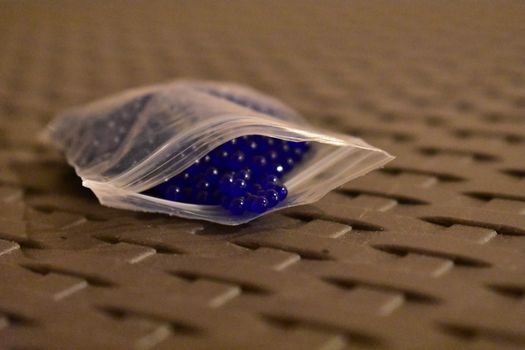 Tiny Blue Orbs in a Plastic Pouch on a Lattice Table