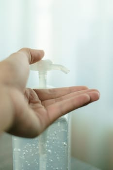 Man hands using wash hand sanitizer gel pump dispenser. Clear sanitizer in pump bottle, for killing germs, bacteria and virus.