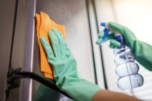 Women hands in rubber green gloves cleaning the Refrigerator at home kitchen, for corona virus or Covid-19 protection.