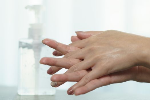 Female hands using wash hand sanitizer gel pump dispenser. Clear sanitizer in pump bottle, for killing germs, bacteria and virus.