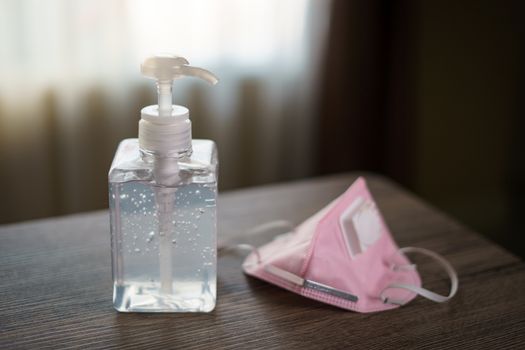 Antibacterial transparent hand sanitizer gel in a plastic bottle with surgical mask.