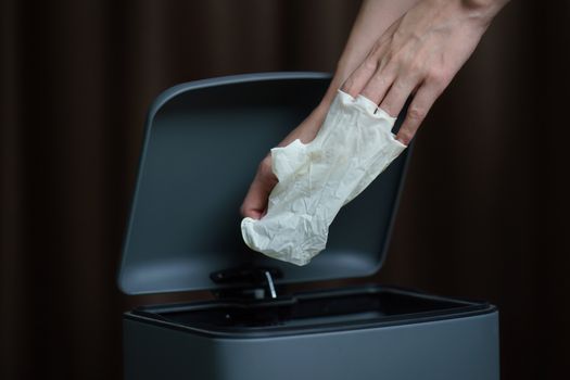 Hand putting used dirty surgical glove to a garbage bin. Mask protect dust and corona virus in trash.