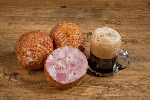 Ham sausage and mug of dark beer on a wooden desk