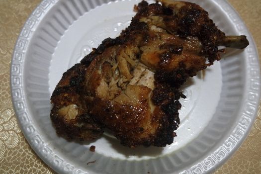 Close up of roasted chicken pieces in a white plate served for meal. Meat background for restaurant advertisements