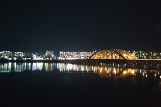 Night view of a beautiful scene of bridge over sea water in the evening time with colorful lights.