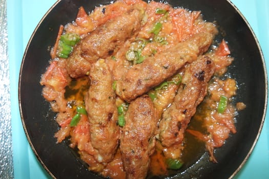 Closeup view of delicious spicy home made fried kebab with green mint leaves and green pepper sprinkled on it