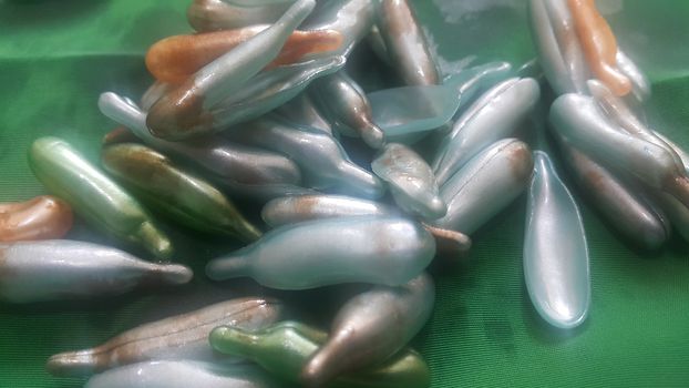 Colorful shiny bright oil capsule spread over a green background. Olden opaque oil capsules.
