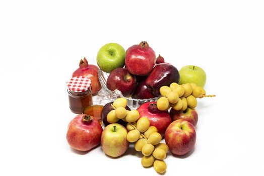 Rosh Hashanah, Jewish New Year, Traditional Symbols, Honey in a glass jar, Pomegranates, Dates, Red And Green Apples. Isolated On A White Background