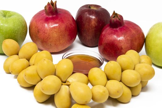 Rosh Hashanah, Jewish New Year, Traditional Symbols, Honey in a glass jar, Pomegranates, Dates, Red And Green Apples. Isolated On A White Background