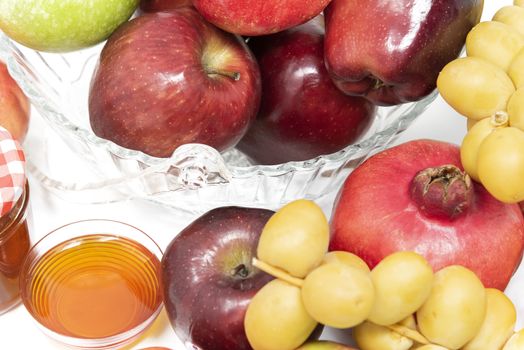 Rosh Hashanah, Jewish New Year, Traditional Symbols, Honey in a glass jar, Pomegranates, Dates, Red And Green Apples. Isolated On A White Background