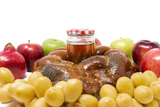 Rosh Hashanah, Jewish New Year, Traditional Symbols, Honey in a glass jar, Pomegranates, Dates, Red And Green Apples, Challah Bread. Isolated On A White Background