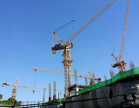 Construction site and yellow crane and building and blue sky.