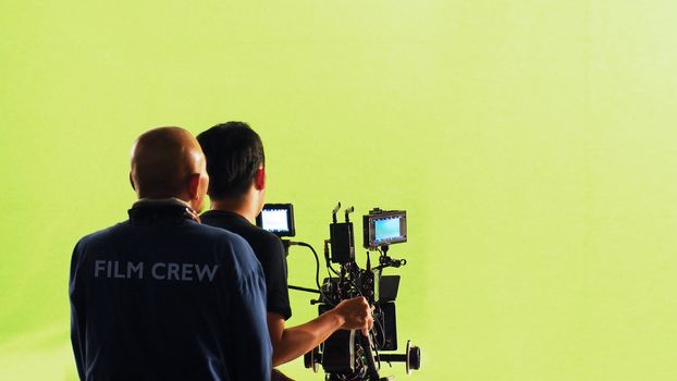 Photographer team and film crew and high definetion online video camera and green screen background for make movie shooting in big studio.