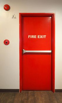 Emergency fire exit door and red color and white wall in building.