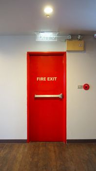 Emergency fire exit door and red color and white wall in building.