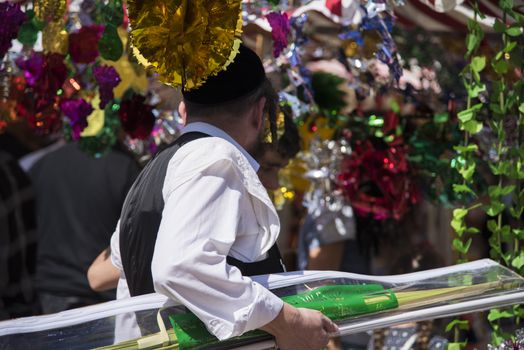 Jewish man wearing kippah. Sukkot's four species festival. Palm branch. Sukkah decorations