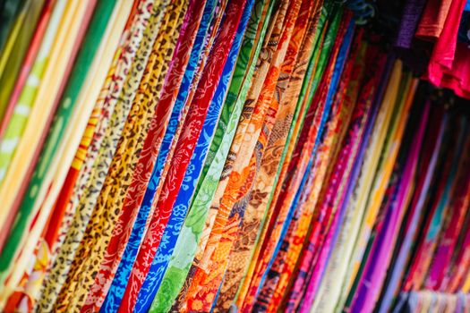 Colorful beautiful fabrics hang on a rack in a market in Ubud, Bali, Indonesia