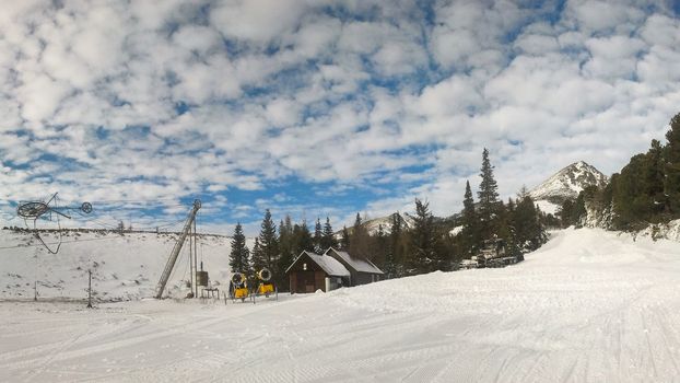 Empty red piste on Strbske pleso, Solisko ski resort on sunny spring day with dramatic clouds in the background and groomed snow in foreground. Vysoke Tatry, Slovakia