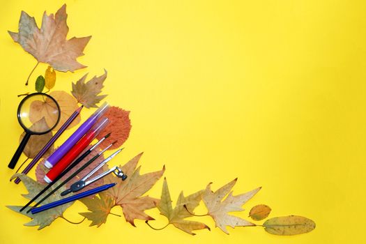 school stationery and autumn leaves on a yellow background, copy space, mockup blank.