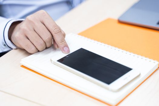 A picture of a business person pointing at a smartphone in a notebook