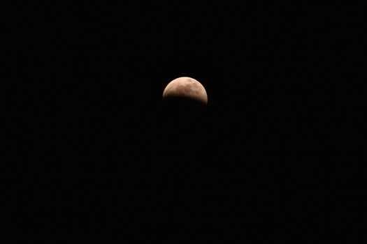 A Reddish Crescent Moon in a Pure Black Sky
