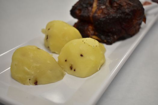 Three Sliced Yuca Potatos Plated Next to a Rotisserie Chicken Breast