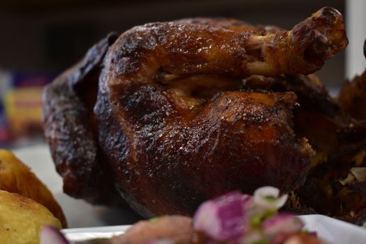 Rotisserie Chicken on a White Plate on a Wooden Table With Potatoes and a Small Salad Next to It