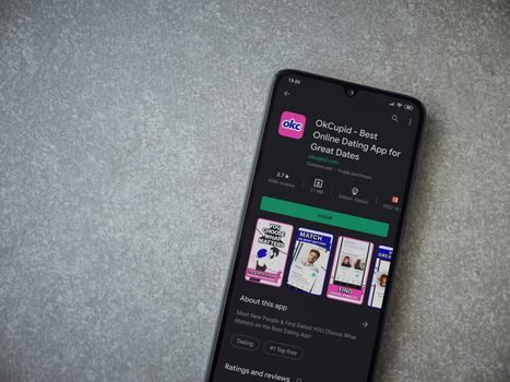Lod, Israel - July 8, 2020: OkCupid app play store page on the display of a black mobile smartphone on ceramic stone background. Top view flat lay with copy space.