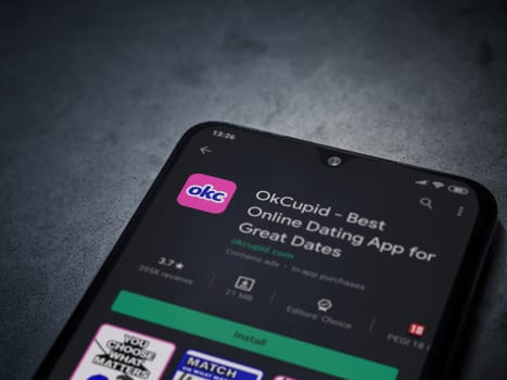 Lod, Israel - July 8, 2020: OkCupid app play store page on the display of a black mobile smartphone on dark marble stone background. Top view flat lay with copy space.