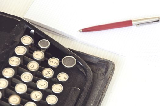 an old black typewriter next to a white sheet of paper with a red pen. Journalism and writing tools. Storytelling and creative activity