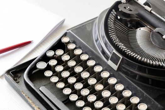 an old black typewriter next to a white sheet of paper with a red pen. Journalism and writing tools. Storytelling and creative activity