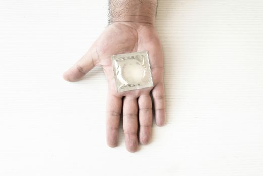 a condom packed on the palm of a male hand. Health and contraception. Prevention of sexually transmitted diseases. Safe sex