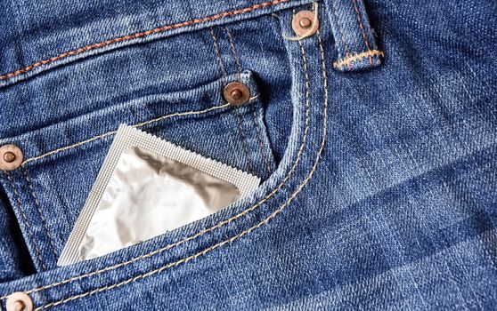 A condom pops out of the front pocket of a pair of jeans. Prevention of sexually transmitted diseases. Safe sex