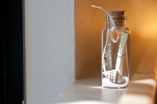 Little strip message in a bottle of sand and shell