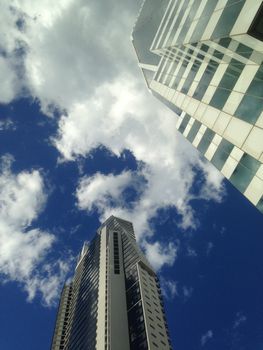 Look up to see blue sky and corporate buildings