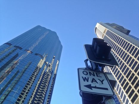 One way traffic sign under corporate buildings blue sky