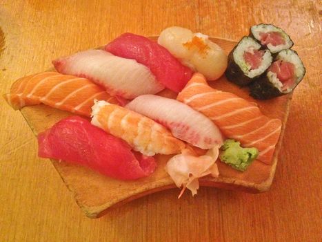 Mixed fresh Japanese sushi platter served on wooden plate and eat with chopsticks