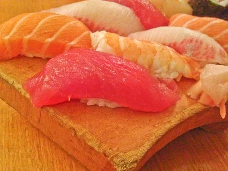 Mixed fresh Japanese sushi platter served on wooden plate and eat with chopsticks