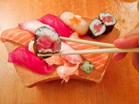 Mixed fresh Japanese sushi platter served on wooden plate and eat with chopsticks