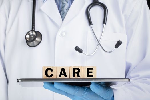 A doctor in white coat holding a plate with letter blocks spelling care. Health care concept.