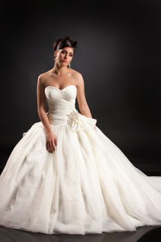 Young beautiful woman in a wedding dress on a black studio background