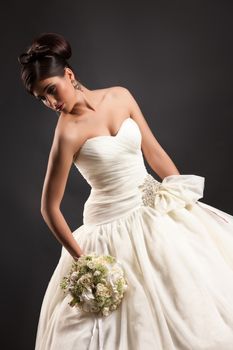 Young beautiful woman in a wedding dress on a black studio background