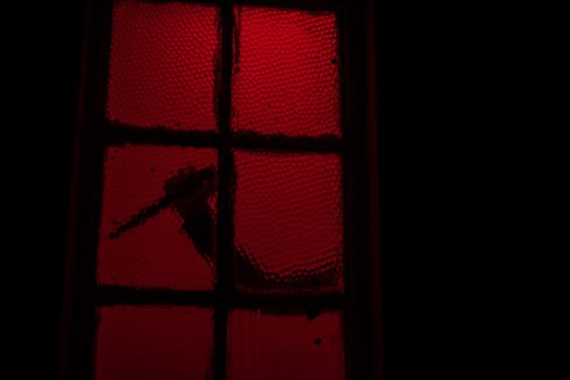 Silhouette of hand with knife seen in window