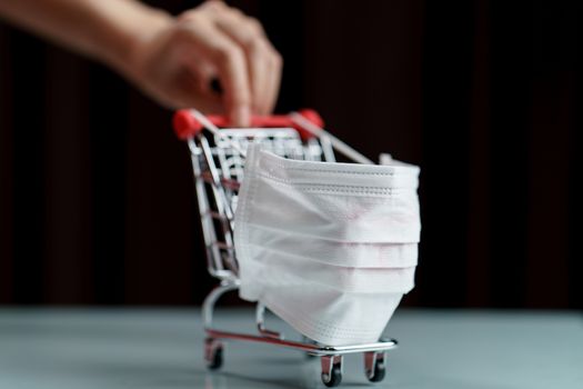 Hands pushing shopping cart with protective face mask corona virus or Covid-19 protection.