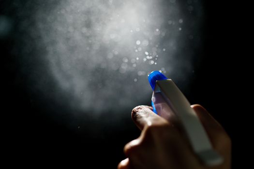 Woman's hands with blue foggy spraying disinfectant to stop spreading coronavirus or COVID-19.