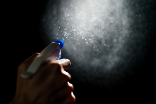 Woman's hands with blue foggy spraying disinfectant to stop spreading coronavirus or COVID-19.